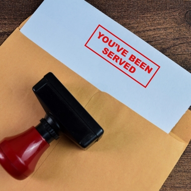 Envelope with "you've been served" stamped on a protruding document.