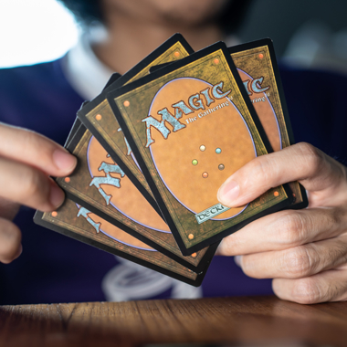A person holding several Magic The Gathering cards in their hands.