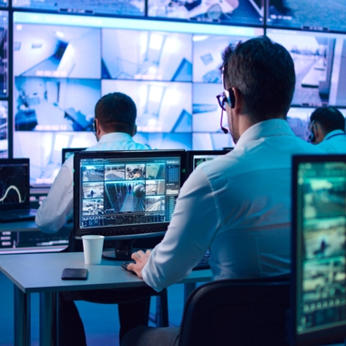Man sitting at a computer watching surveillance video.