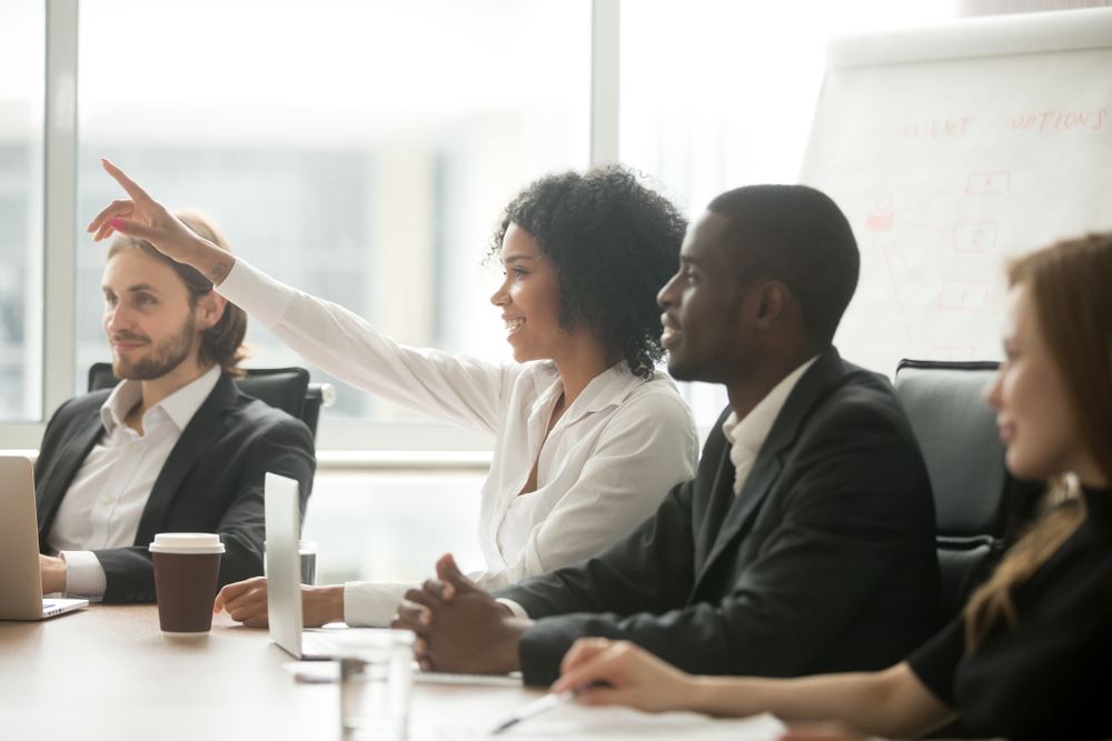 Women raising her hand in a meeting.