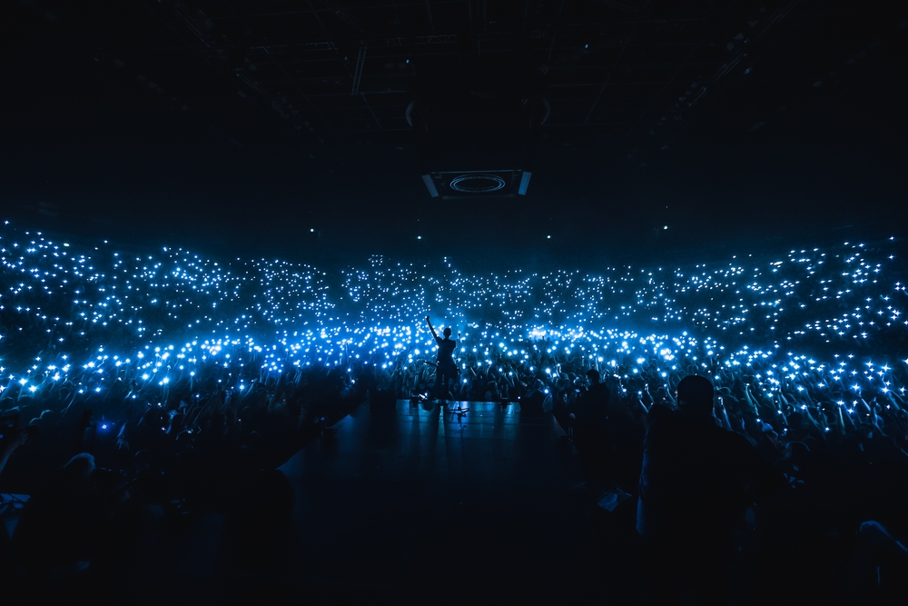 A concert with blue lights illuminating a dark stadium