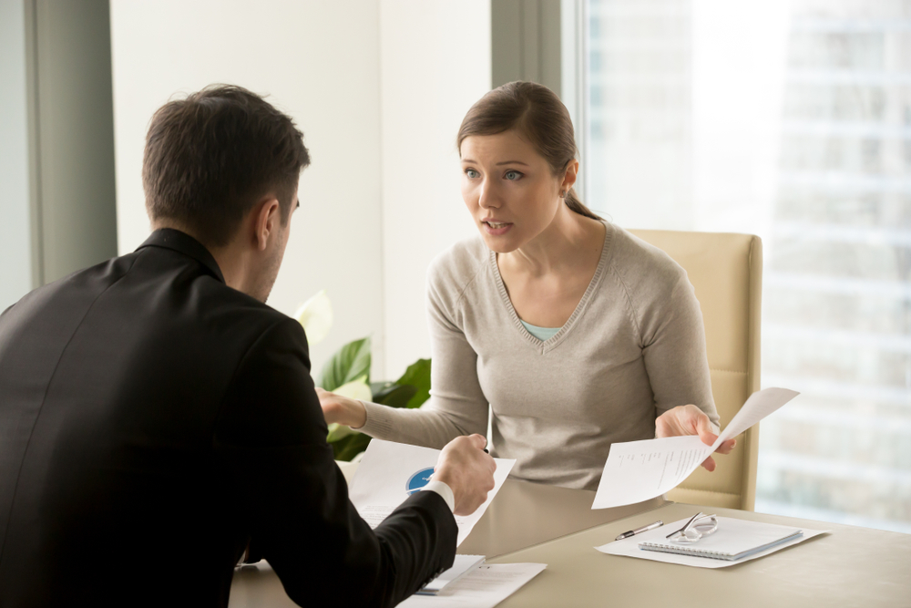 A woman negotiating with emotion with a man across a desk.
