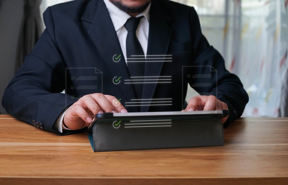 A man typing on a tablet with a translucent icon of a document hovering above.