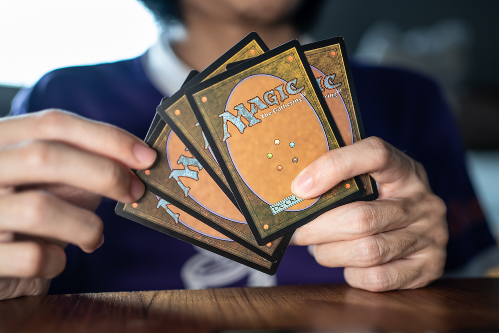 A person holding several Magic The Gathering cards in their hands.