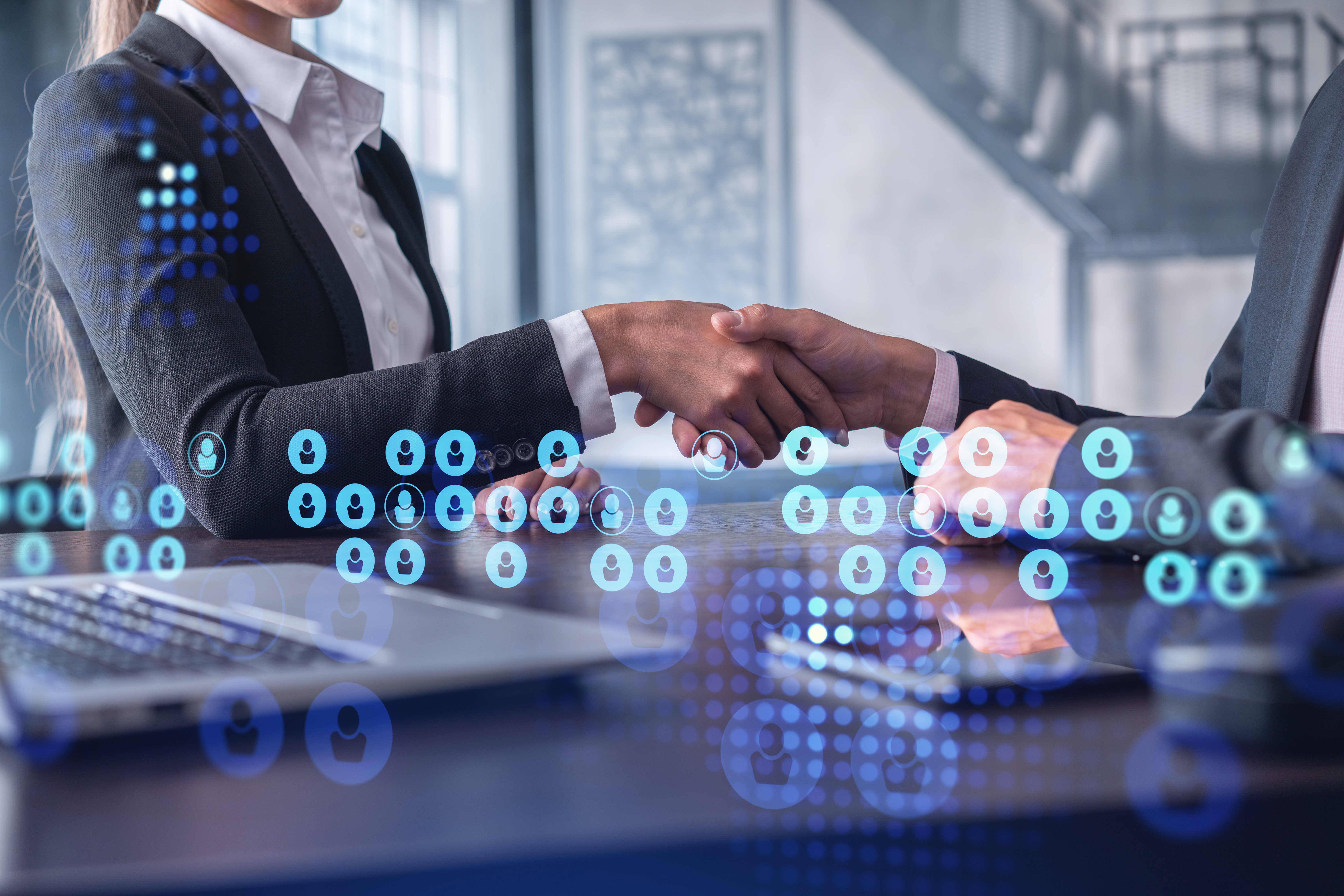 Two people shaking hands, surrounded by people icons in different colors