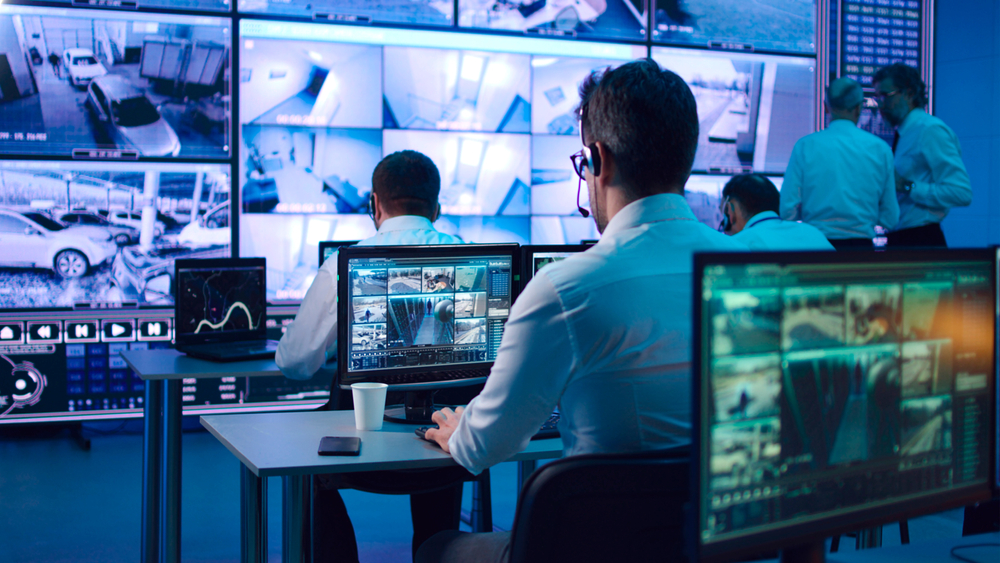 Man sitting at a computer watching surveillance video.